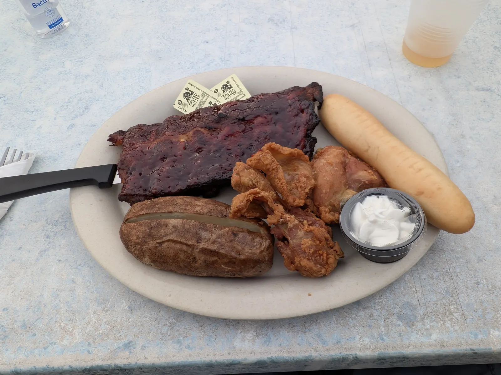 A plate of ribs, broasted chicken, baked potato and breadstick at Edge-O-Dells
