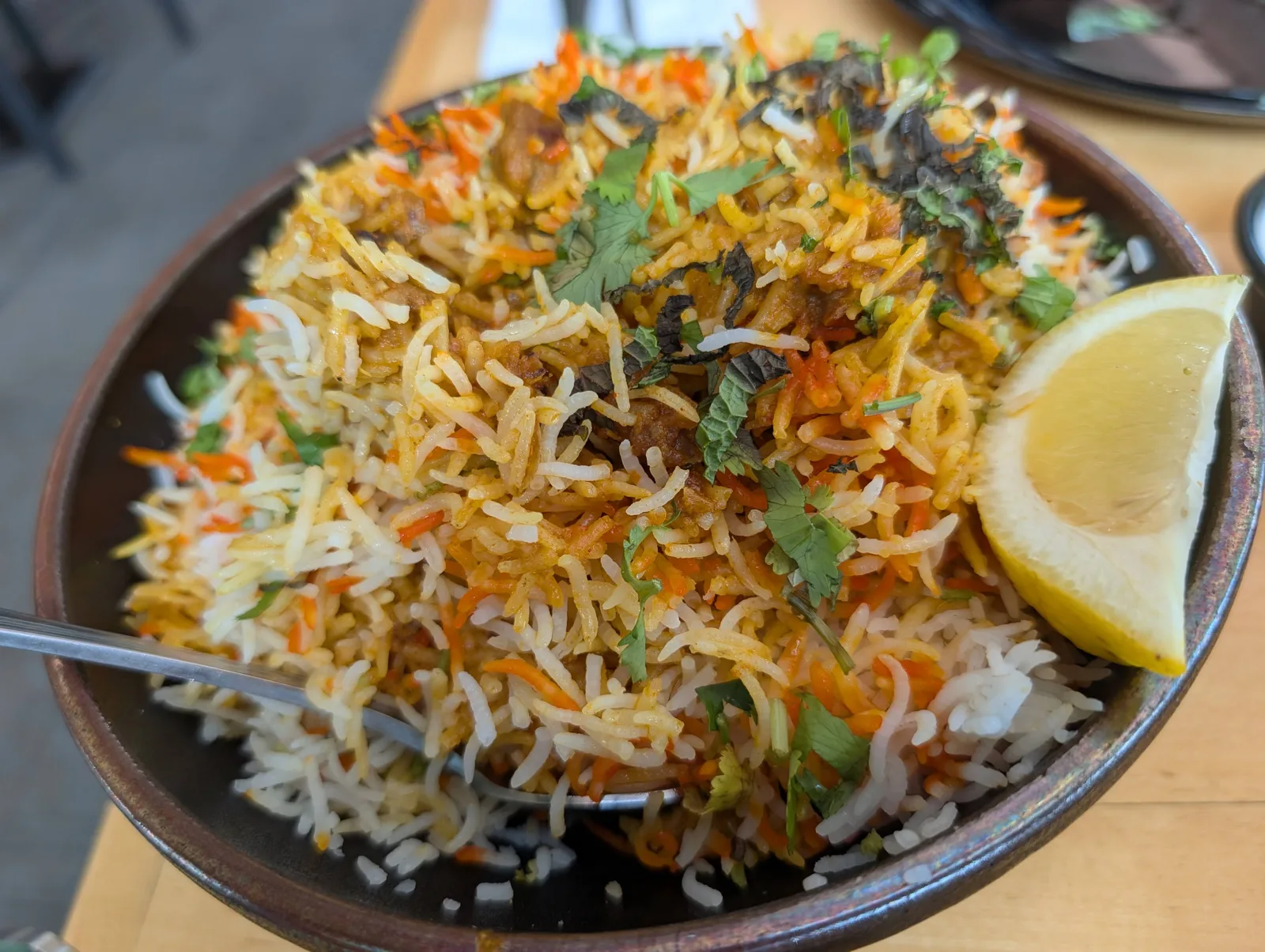 A bowl of biryani with a lemon wedge at Swagat